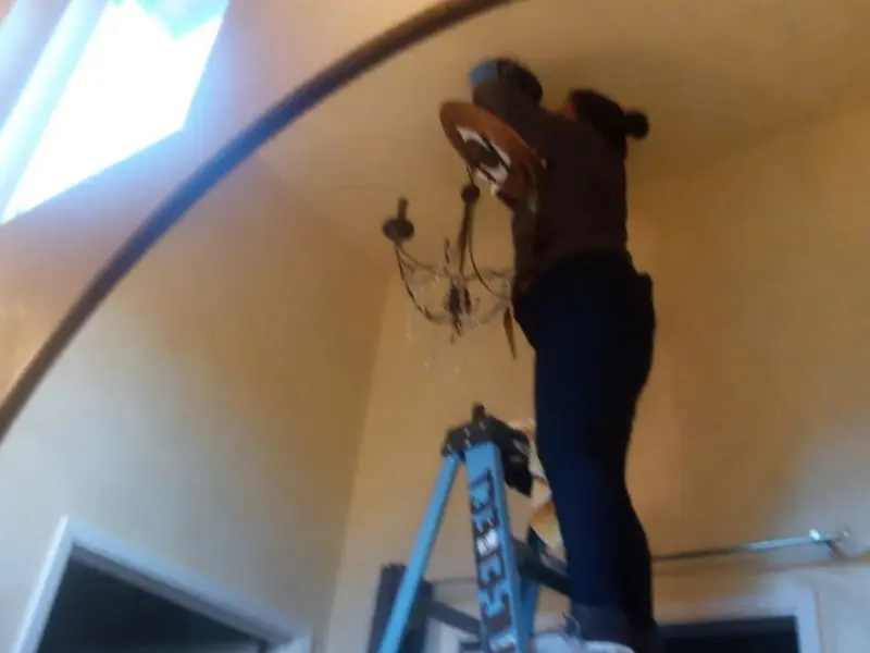 Electrician installing a chandelier in a Bridge City residence